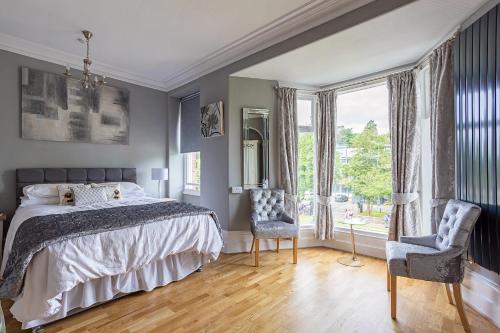 a bedroom with a bed and two chairs and a window at Glenholmekendal in Kendal