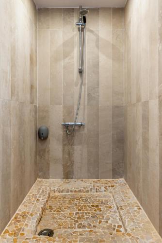 La salle de bains est pourvue d'une douche et d'un sol en pierre. dans l'établissement Appartement en front de mer avec terrasse et vue mer, à Arromanches-les-Bains