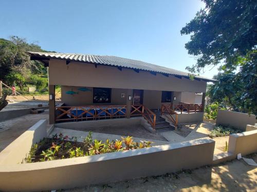 a small building with a fence and some plants at WHITE SHARK RESORT in Ponta do Ouro