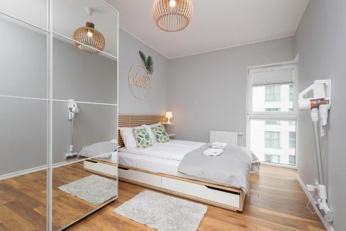 a white bedroom with a bed and a mirror at Albatross Towers Przymorze Apartments by Renters in Gdańsk