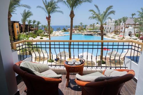 a balcony with chairs and a table with a view of a pool at Royal Savoy Sharm El Sheikh in Sharm El Sheikh