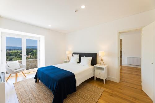 a white bedroom with a bed and a chair at Linden Tree House A and B in Caldelas