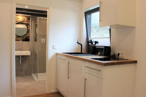 cocina blanca con lavabo y ducha en Ferienapartment Rebwinkel, en Burgen