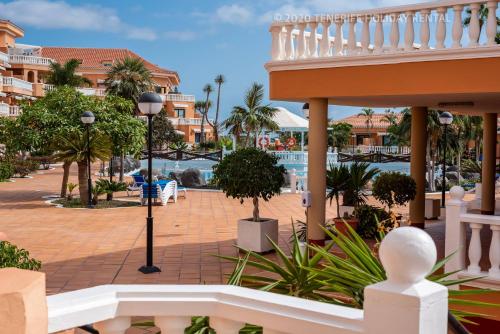 a balcony of a resort with a pool and palm trees at Tenerife South Apartments in Playa de las Americas