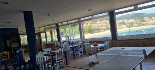 科爾庫維翁的住宿－Albergue en Corcubion playa de Quenxe，用餐室配有乒乓球桌和椅子