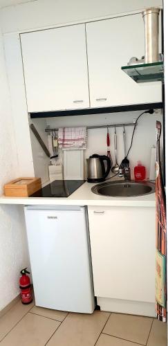 a small kitchen with white cabinets and a sink at SUITE-XXI City View Hotelturm Augsburg in Augsburg