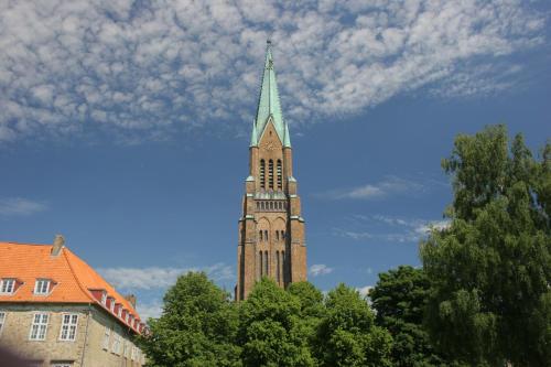 a tall tower with a green steeple on a building at Hotel an der Schlei Garni in Fahrdorf