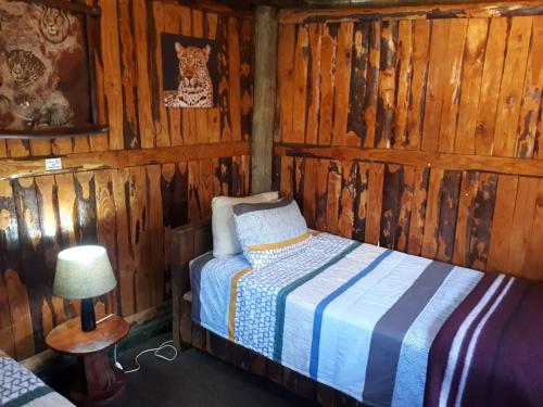 a bedroom with a bed in a log cabin at ThabaNkwe Bushveld Inn in Thabazimbi