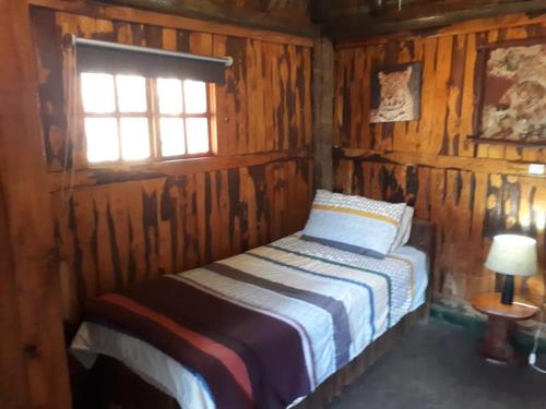 a bedroom with a bed in a wooden cabin at ThabaNkwe Bushveld Inn in Thabazimbi