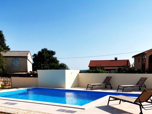 a swimming pool with two chairs next to a wall at Villa Mira Garica in Garica