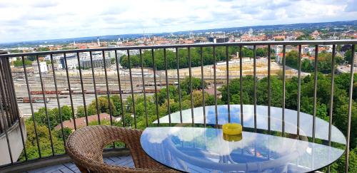 a glass table and two chairs on a balcony at SUITE-XXI City View Hotelturm Augsburg in Augsburg