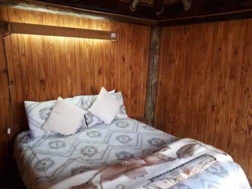 a bed in a room with a wooden wall at ThabaNkwe Bushveld Inn in Thabazimbi