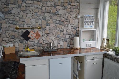 a kitchen with a stone wall and a sink at Bodasjön in Boda Glasbruk