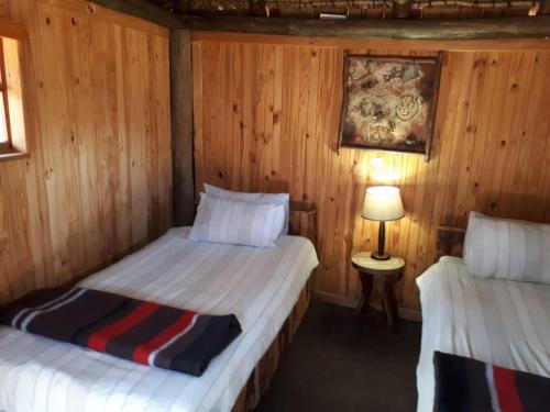 two beds in a room with wooden walls at ThabaNkwe Bushveld Inn in Thabazimbi