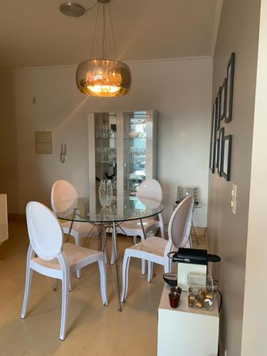 a dining room with a glass table and white chairs at Andy Apto Menino Deus/Cidade Baixa/Orla in Porto Alegre