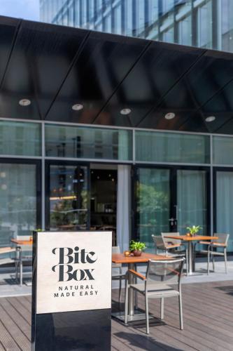 a sign in front of a building with tables and chairs at INNSiDE by Meliá Düsseldorf Seestern in Düsseldorf
