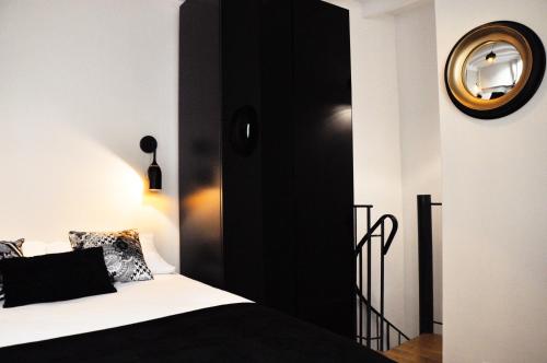 une chambre avec un lit noir et blanc et un miroir dans l'établissement Duplex de charme au Coeur de Montmartre, à Paris