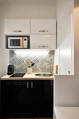 une cuisine avec un évier et un micro-ondes dans l'établissement Duplex de charme au Coeur de Montmartre, à Paris