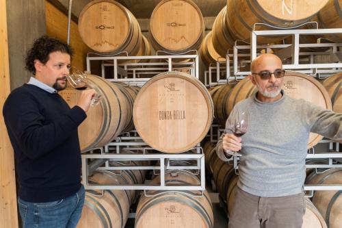 two men standing in front of a bunch of wine barrels at Conca Bella Boutique Hotel & Wine Experience in Vacallo