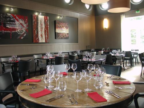 un restaurante con una mesa grande con copas de vino. en Hôtel la Régie, en Briey