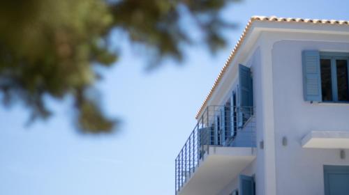 a white apartment building with a blue balcony at Akasha Suite III in Vathi