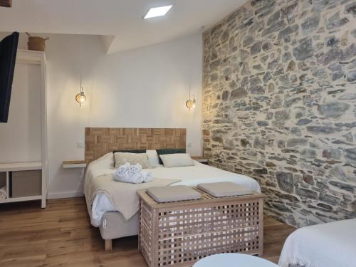 une chambre avec un lit et un mur en pierre dans l'établissement Osemae Immobilier - Redon Port-Chatelêt, à Redon