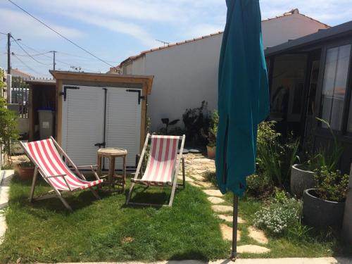 2 chaises longues et un parasol dans la cour dans l'établissement La Galerie, à La Chaume