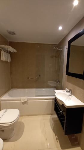 
a white toilet sitting next to a bath tub in a bathroom at Hotel Versailles in Mar del Plata
