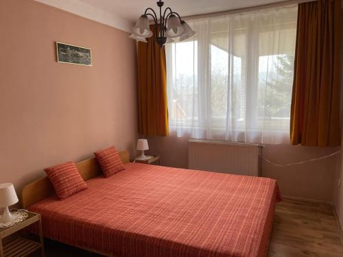 a bedroom with a red bed and a window at Tornyos Vendégház Mátraderecske in Mátraderecske