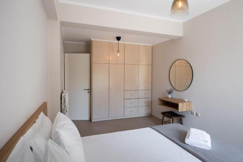 a white bedroom with a bed and a mirror at La Strada Apartment in Lefkada
