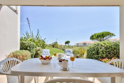 - une table blanche avec des boissons et des fruits sur la terrasse dans l'établissement Appartement avec jardin partagé pour 4, à Les Sables-dʼOlonne