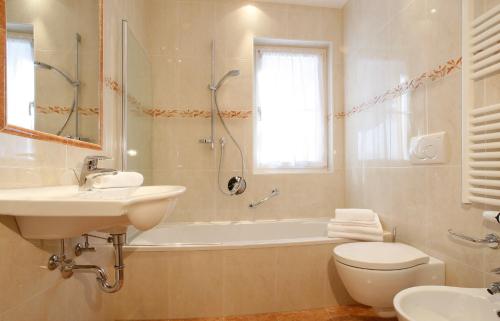 łazienka z umywalką, wanną i toaletą w obiekcie Apartments Antines w mieście Selva di Val Gardena