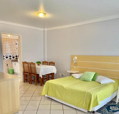 1 dormitorio con 1 cama, mesa y sillas en Residencial Nápole en Torres