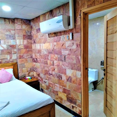 a brick wall in a room with a bed and a bathroom at Hotel Vista Inn DHA in Rawalpindi