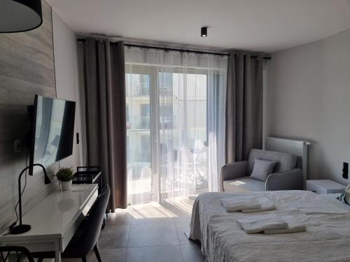 a bedroom with a bed and a desk and a television at Apartamenty ApartPark - visitopl in Świnoujście