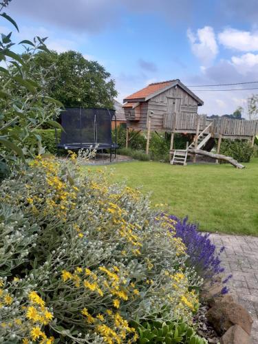 a garden with a wooden house and flowers at vakantiehuis zoetendaal in Reningelst
