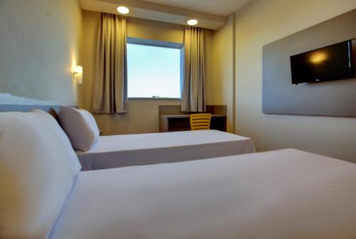 a hotel room with two beds and a window at Transamerica FIT Lucas do Rio Verde in Lucas do Rio Verde