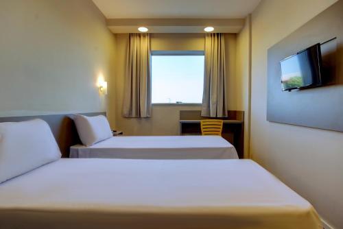 a hotel room with two beds and a television at Transamerica FIT Lucas do Rio Verde in Lucas do Rio Verde