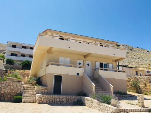 une maison avec des escaliers en face d'un bâtiment dans l'établissement Apartments Gubo, à Pag