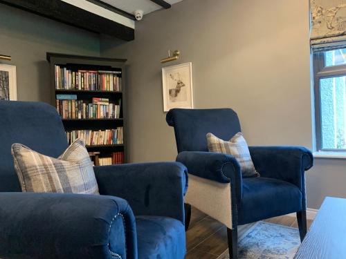 dos sillas azules y una estantería con libros en The Cedar Country Hotel, en Bellway