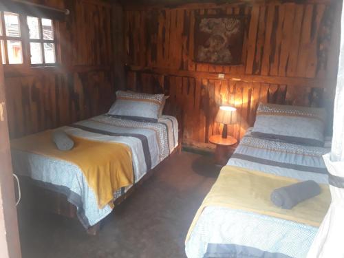 three beds in a room with wooden walls at ThabaNkwe Bushveld Inn in Thabazimbi