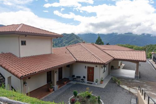 a house with a red roof with mountains in the background at Inn The Coffeepot - Boutique Hotel in Boquete