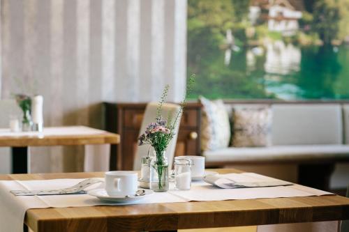 a table with cups and a vase of flowers on it at Seehotel Billroth in Sankt Gilgen