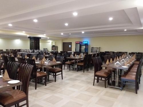 Habitación grande con mesas y sillas. en Hotel Sravasti Residency, en Katra