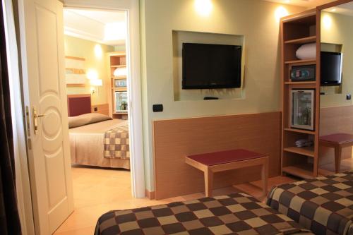 a hotel room with two beds and a flat screen tv at Artemis Hotel in Cefalù