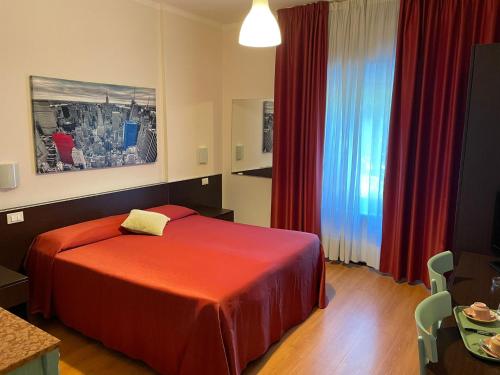 a hotel room with a red bed and a window at Hotel Stazione del Sole in Albenga