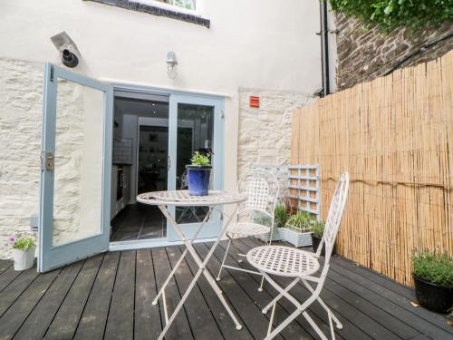 a patio with a table and chairs on a deck at The Old Dairy in Torpoint