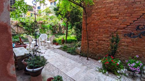 un patio con sillas y flores y una pared de ladrillo en Tiepolo 3, en Venecia