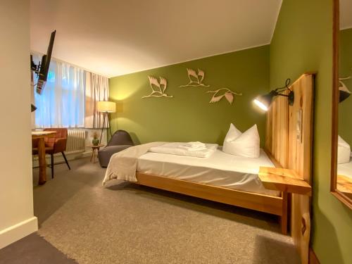a bedroom with a bed and green walls with birds on the wall at Waldhotel Eiche in Burg