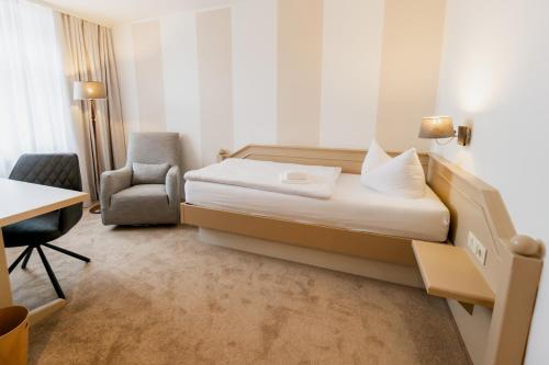 a hotel room with a bed and a chair and a desk at Waldhotel Eiche in Burg
